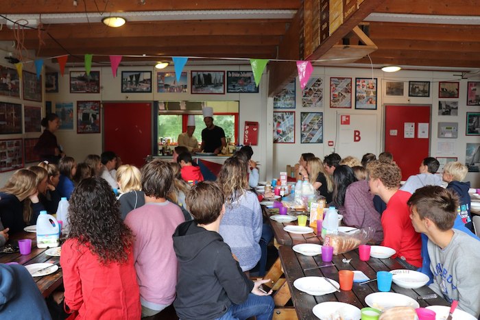 Jongeren zitten aan tafel in de eetzaal tijdens het zeilkamp