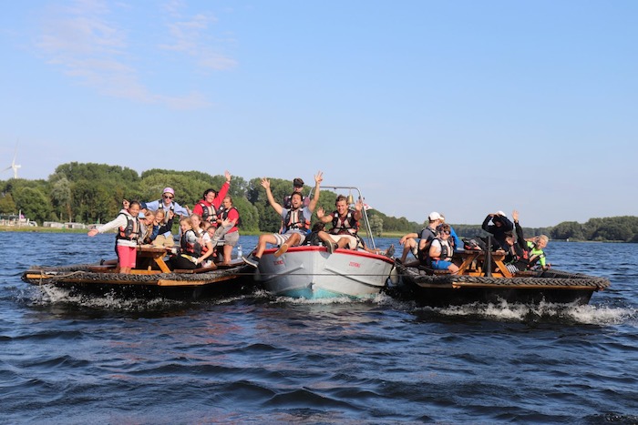 Jongeren poseren vanuit drie boten vanop het meer tijdens het zeilkamp