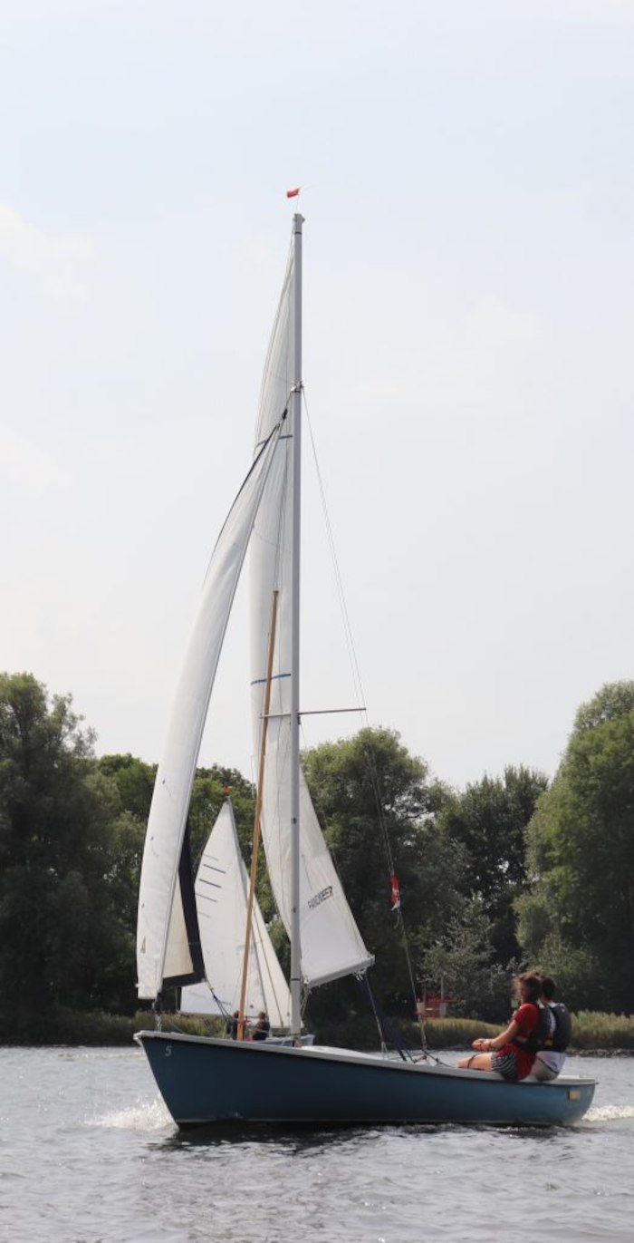 Twee jongeren zitten samen in een zeilboot tijdens het zeilkamp