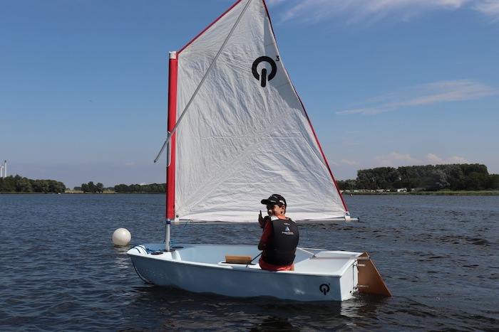 Een jongen zeilt met een optimist op het meer tijdens het zeilkamp
