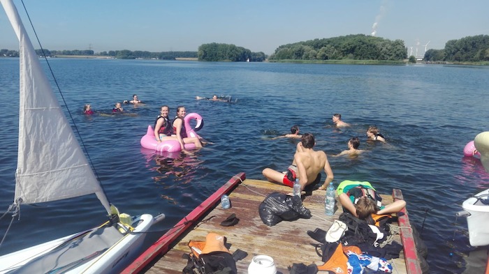 Jongeren relaxen aan het water tijdens het zeilkamp.