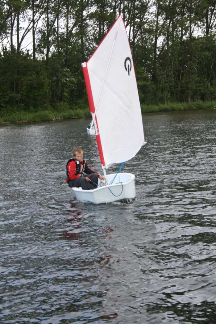 Een kindje zeilt in een optimist tijdens het zeilkamp