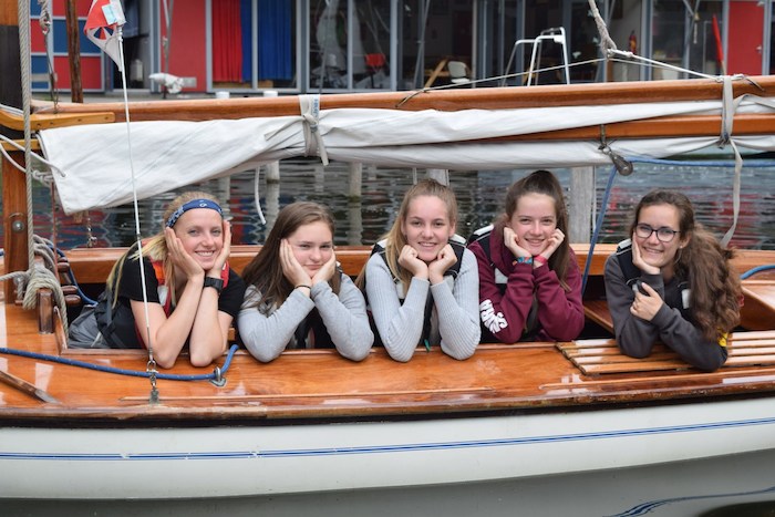 Meisjes poseren lachend aan het water in veiligheidsvest.