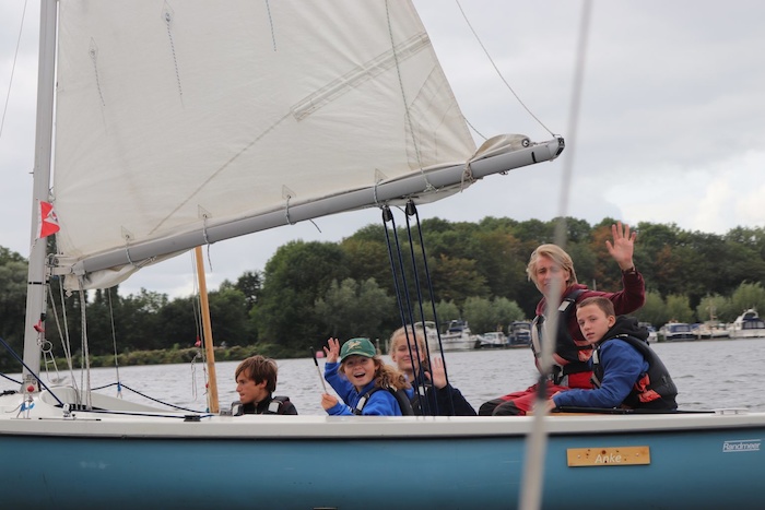 Kinderen trekken er samen met hun begeleider op uit met de zeilboot tijdens het zeilkamp