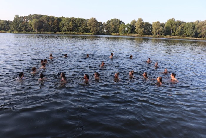 Kinderen en jongeren zwemmen in het verfrissende meer tijdens het zeilkamp