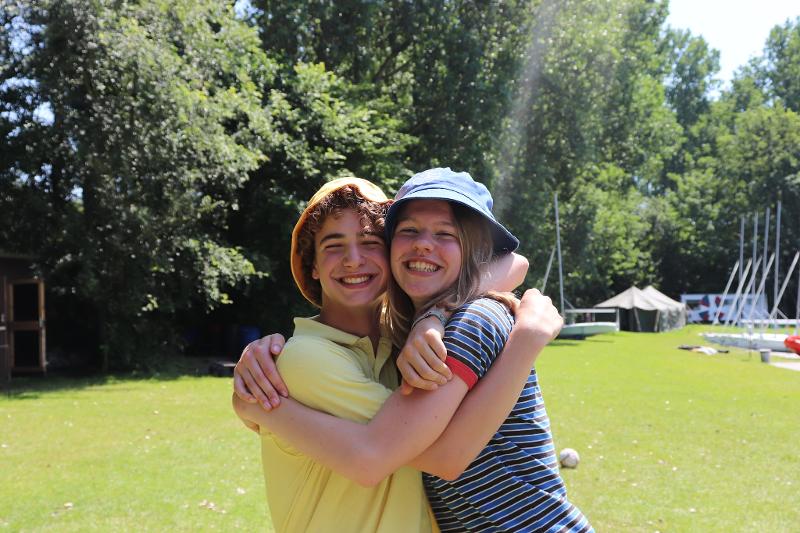 jongen en meisje geven elkaar een knuffel in de zon op het zeilkamp zomervakantie