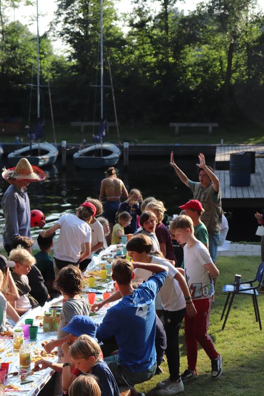 Deelnemers eten diner in de buitenlucht tijdens zeilkamp kinderen