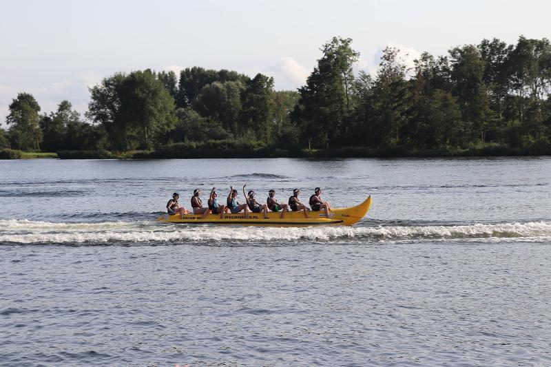 kinderen op een bananenboot in het water zwaaien tijdens zeilkamp kinderen