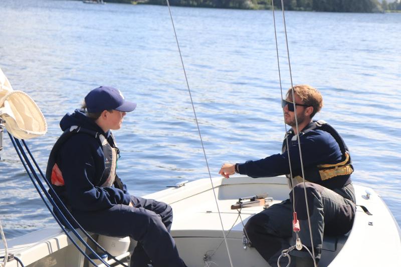 Twee begeleiders praten op de zeilboot tijdens zeilkamp kinderen