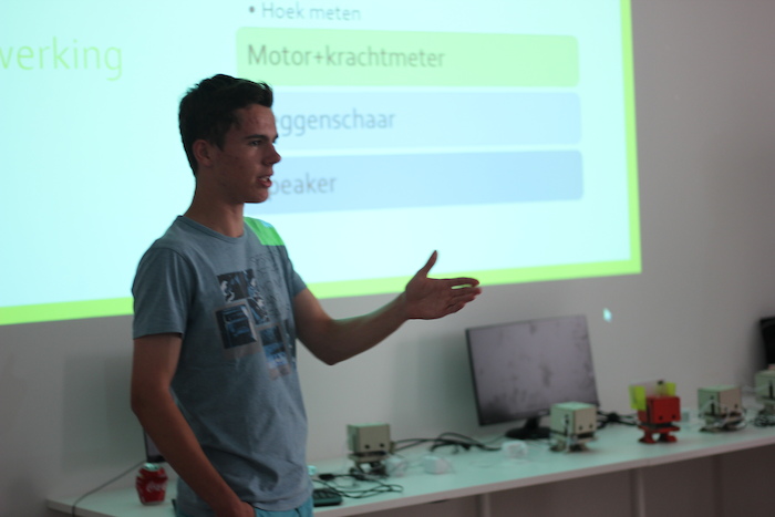 Jongen staat voor de klas op zomerkamp België en geeft uitleg