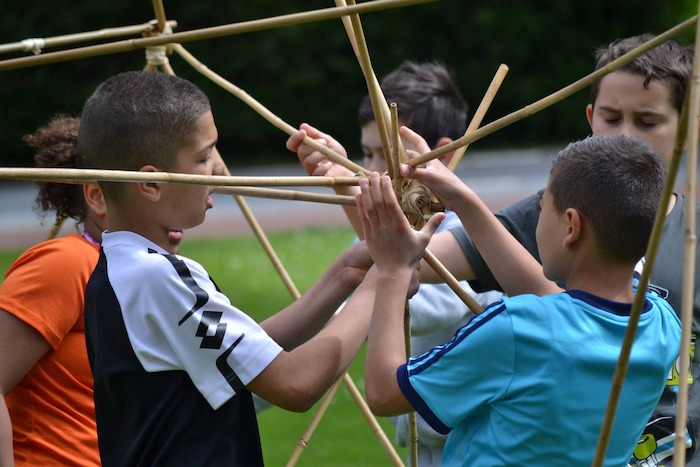 Kinderen bouwen met stokjes tijdens het outdoorkamp in Zuid-Holland.
