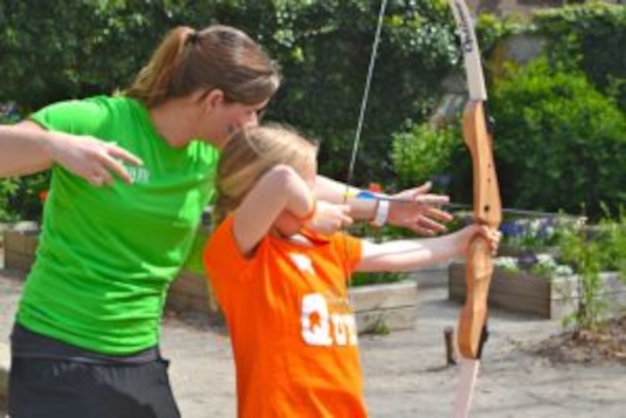 Een meisje leert boogschieten op zomerkamp in Zuid-Holland.