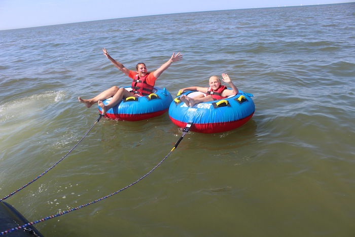 Meisjes zitten in banden op het water, lachen naar de camera.