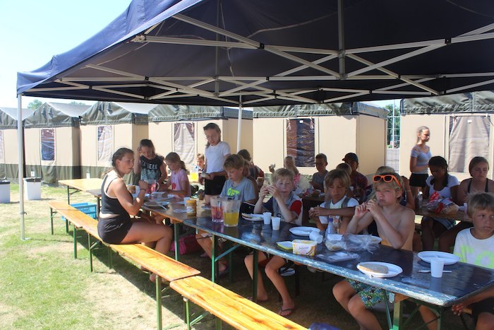 Kinderen genieten van hun lunch tijdens een surfkamp in Zandvoort.