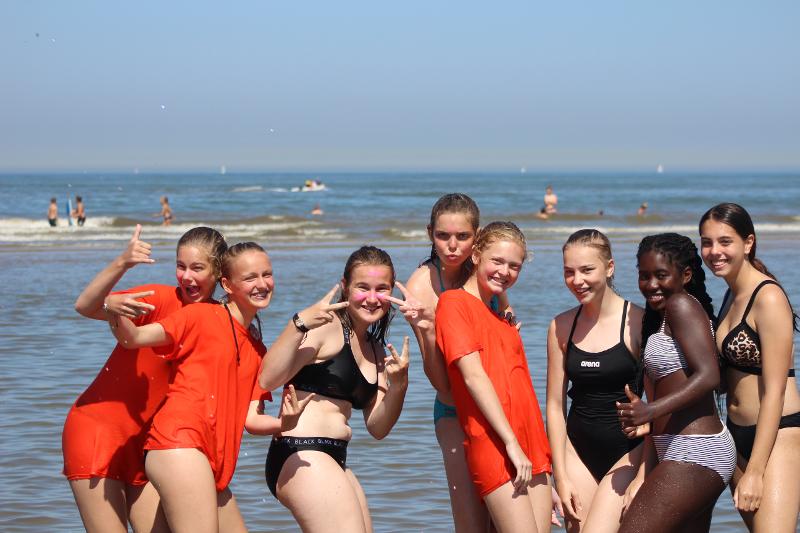 Groep meiden tijdens een last minute kamp staan op een strand in het water