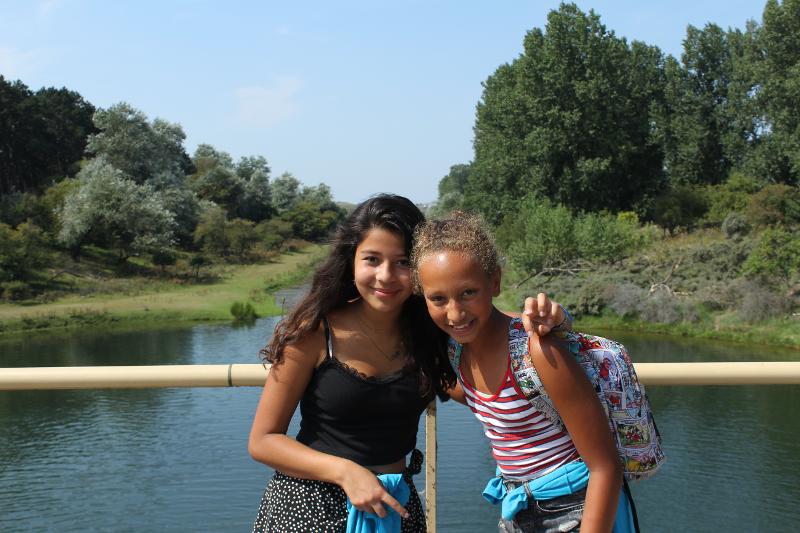 twee meisjes knuffelen voor foto op brug op surfkamp zandvoort zomer
