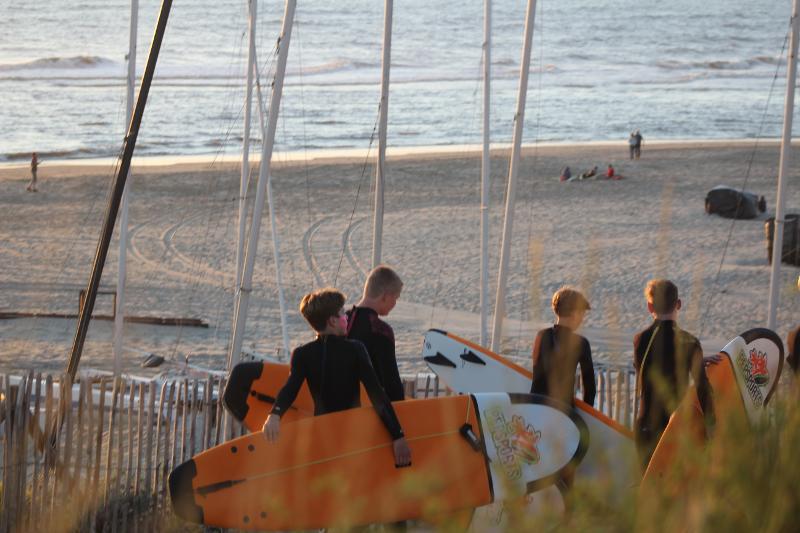 jongens lopen op het zand met hun surfboard op surfkamp zandvoort zomer
