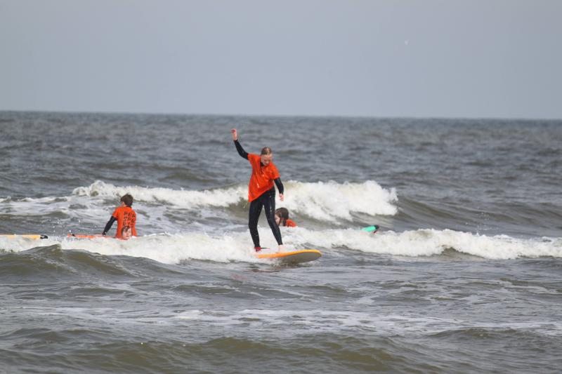 Jongeren staan voor surfboards op strand.