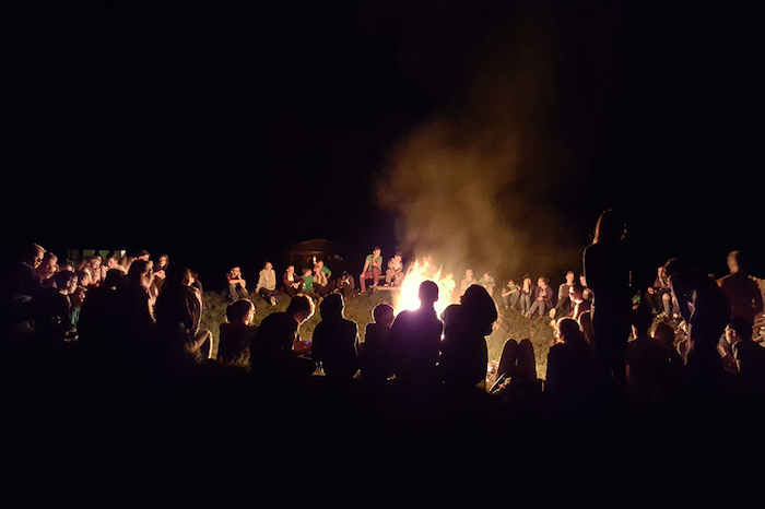 Iedereen verzamelt 's avonds rond het kampvuur tijdens het zomerkamp in Drenthe