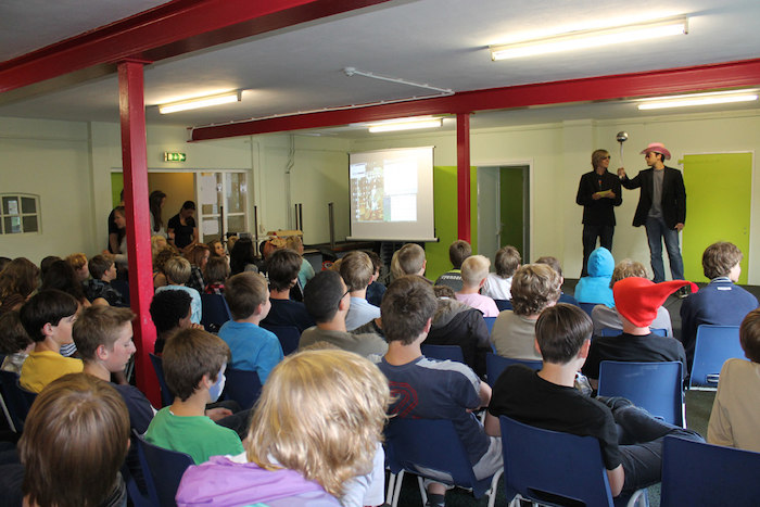 Jongeren kijken naar een toneelspel van de begeleiders tijdens het zomerkamp in Drenthe