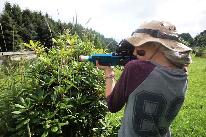 Meisje doet aan paintballen in het bos op meidenkamp