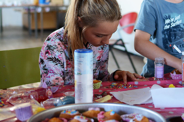 Geconcentreerd versiert meisje cake op zomerkamp Drenthe.