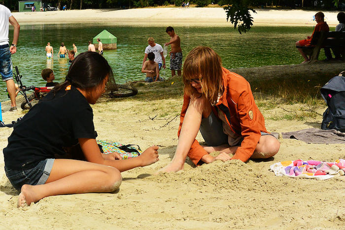 Meisjes chillen aan het strand van de zwemvijver tijdens het girl camp in Drenthe