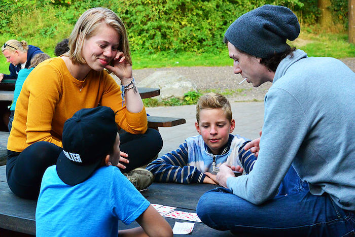 Twee kinderen en twee begeleiders spelen met de kaarten tijdens het avonturenkamp in Drenthe