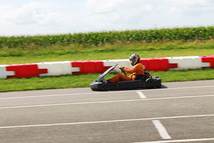 Jongere rijdt op baan in gocart op jeugdkamp.