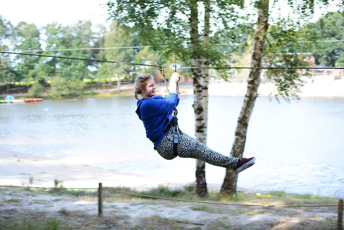 Een meisje vliegt van de zipline naar beneden tijdens het avonturenkamp in Drenthe
