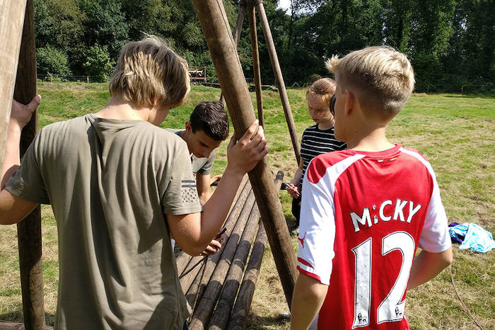 Kinderen bouwen een houten constructie tijdens het survivalkamp.