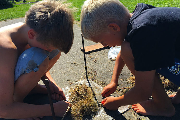 Twee jongen maken vuur tijdens het survivalkamp in Drenthe.