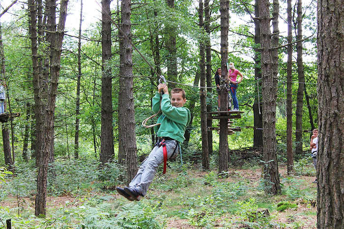Een jongen ziplinet tijdens het survivalkamp.