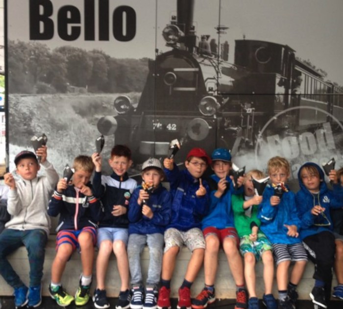 Kinderen poseren lachend op jeugdkamp in Nederland.