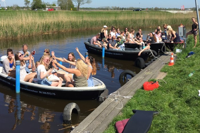 Jongeren zitten in bootjes op kanaal.