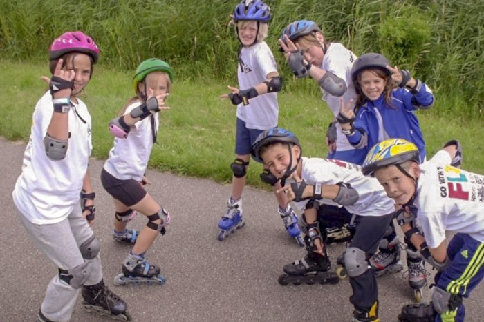Op jeugdkamp in Nederland poseren rolschaatsende kinderen voor de camera.