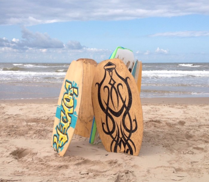 Vijf surfboards staan rechtop in het Nederlandse zand.