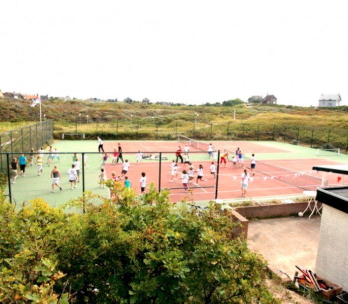 Kinderen in witte shirts spelen voetbal op jeugdkamp in Nederland.
