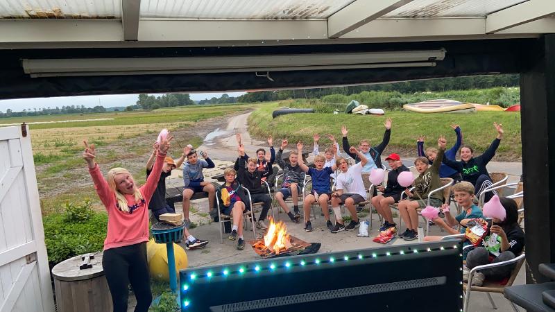 Kinderen rondom het kampvuur tijdens zomerkamp Noord-Holland