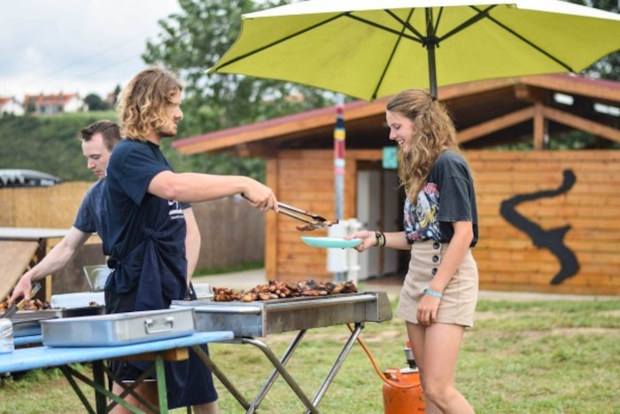 meisje krijgt vlees van de barbecue op surfkamp spanje