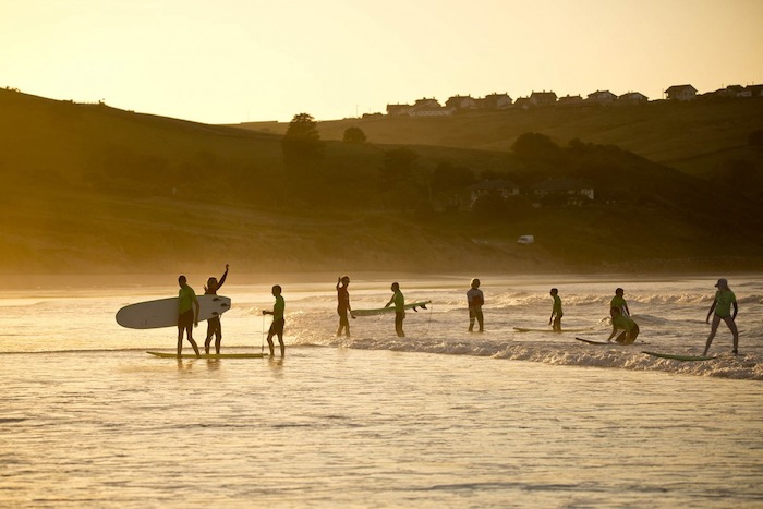 Jeugd loopt over het strand met hun surfboards