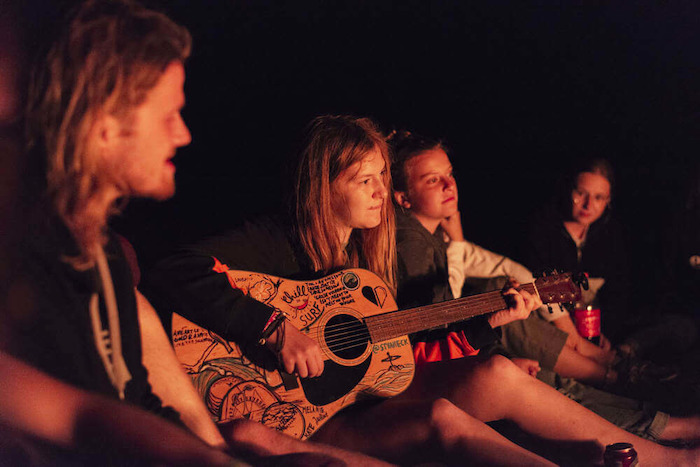Meisje speelt gitaar bij het kampvuur op zonvakantie