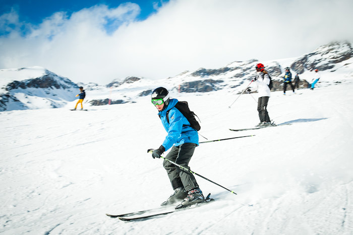 Deelnemer wintersportkamp glijdt besneeuwde berg af op ski's