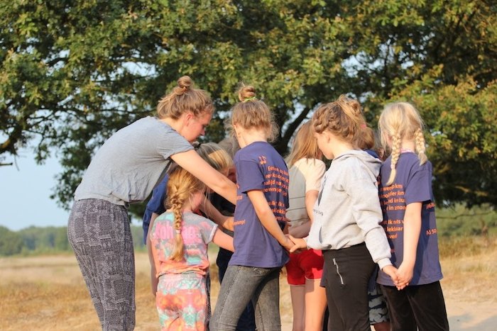 Meisjes spelen groepsspel en houden handen vast op zomerkamp nederland
