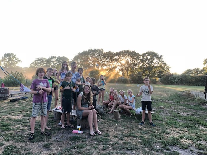 Deelnemers van een survivalkamp in Overijssel kijken naar de camera en lachen op zomerkamp nederland