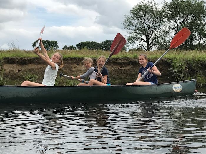 Dolgelukkige meiden varen in kano, lachen en poseren op zomerkamp nederland
