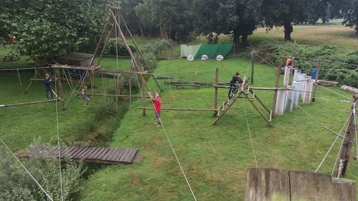 Kinderen klimmen over hindernissenparcours op survival in Overijssel op zomerkamp nederland