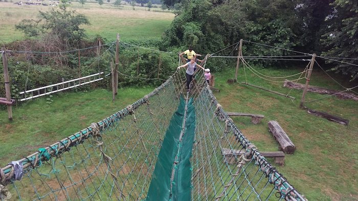 Meisje wandelt over touwbrug op survival in Overijssel op zomerkamp nederland