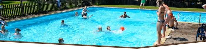 Kids stoeien in azuurblauw zwembad op survivalkamp in Overijssel.
