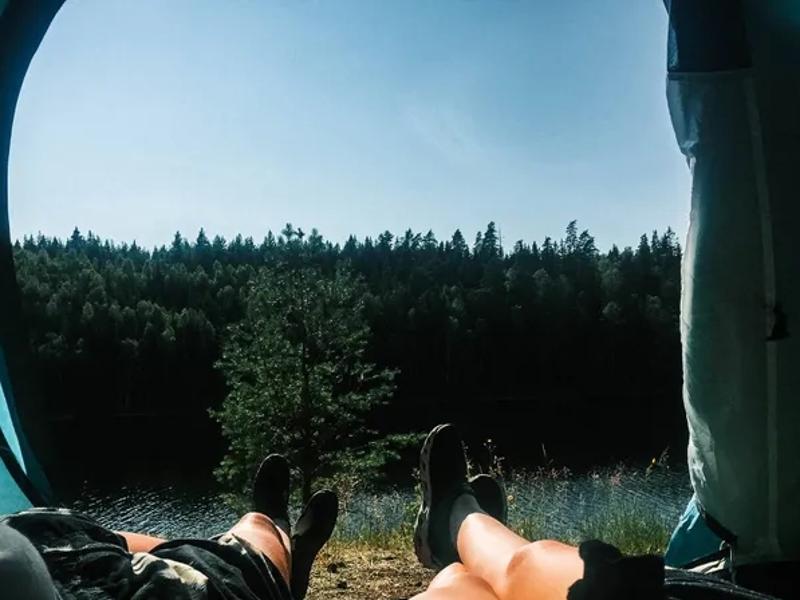 Twee mensen liggen in een tent te genieten van het uitzicht tijdens hun jongerenreis in Zweden